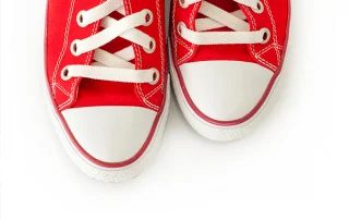 A pair of red canvas sneakers on a white background, the AIDS Walk image used on this press release.